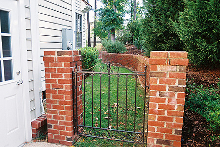A brick fence with a wrought-iron gate
