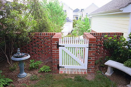 A brick wall with a white picket gate